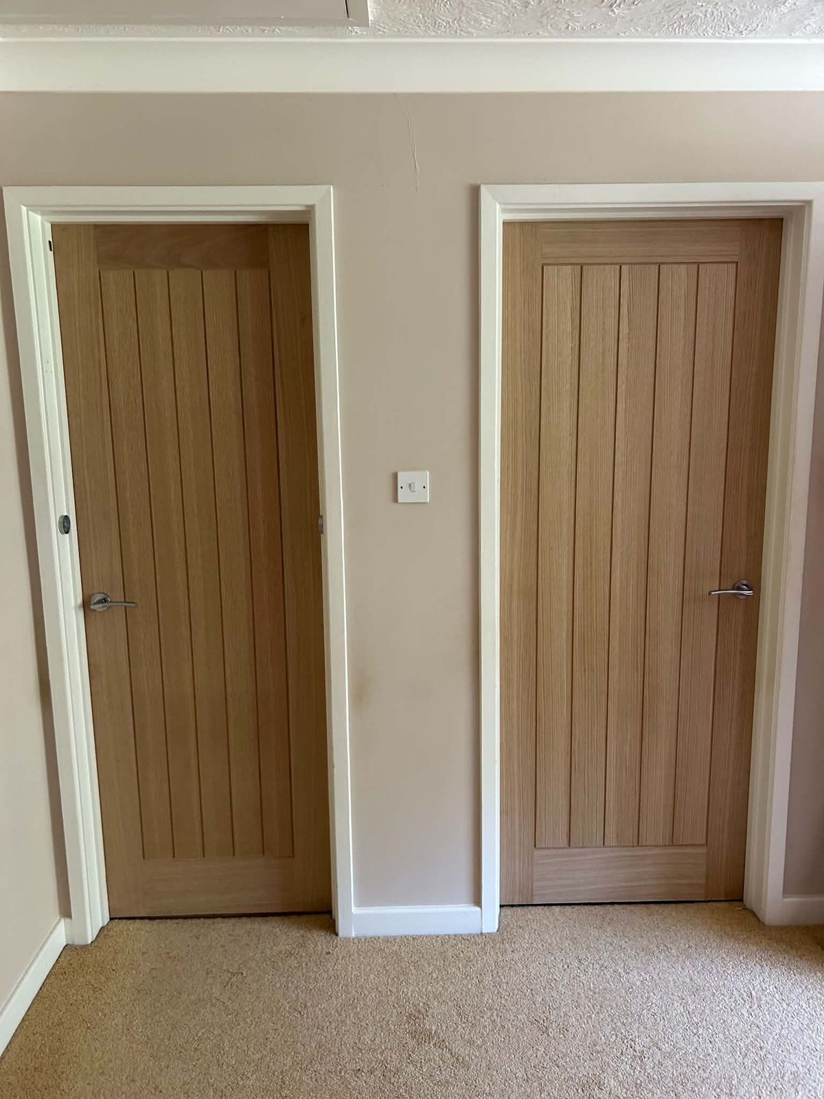 Two oak internal doors with chrome handles on a carpeted landing